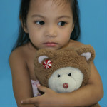 girl hugging teddy bear sad expression